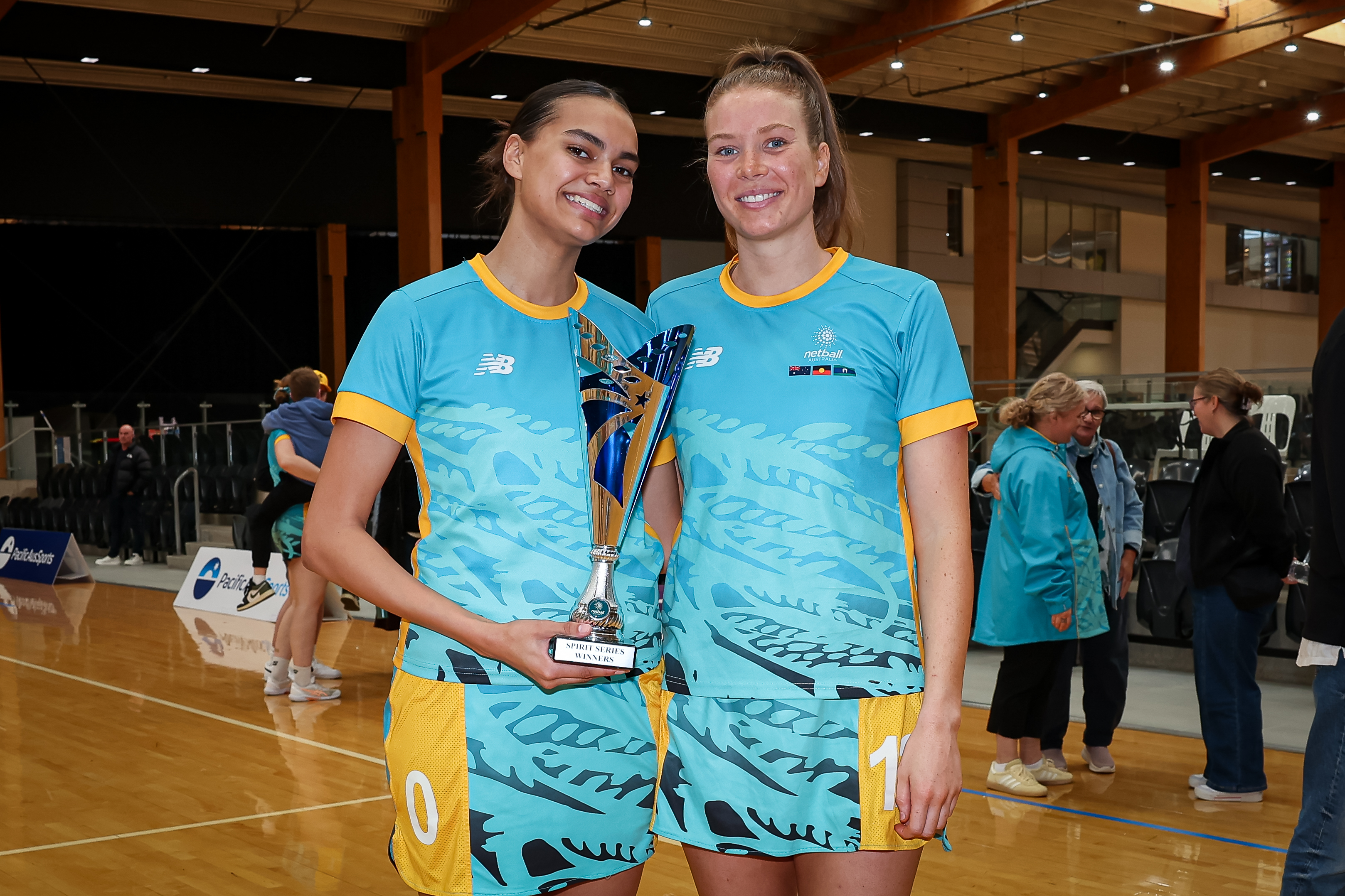 two netballers holding trophy