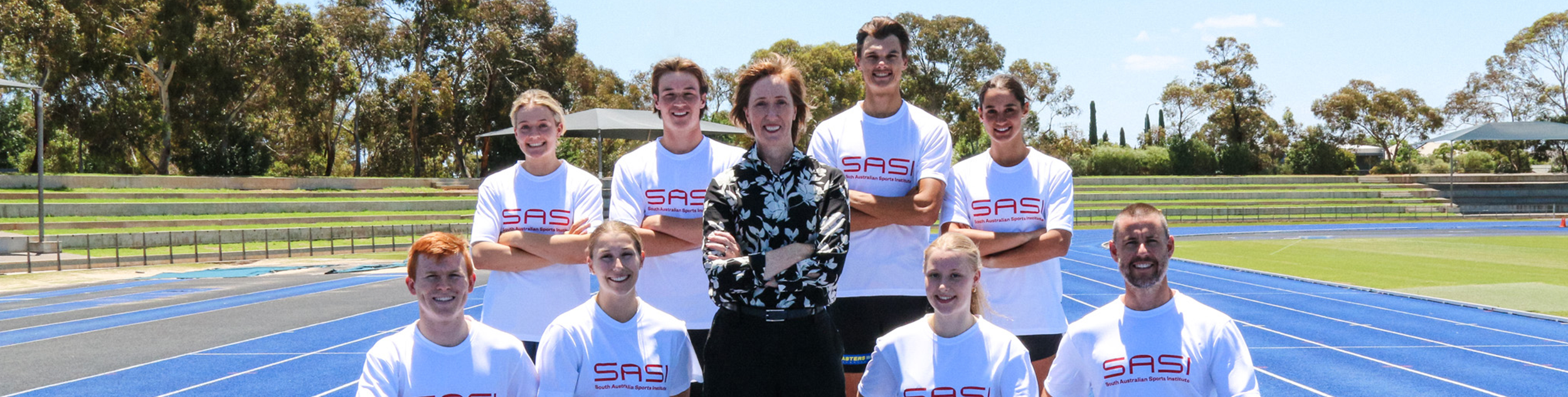 Keren Faulkner surrounded by athletes on a blue athletics track