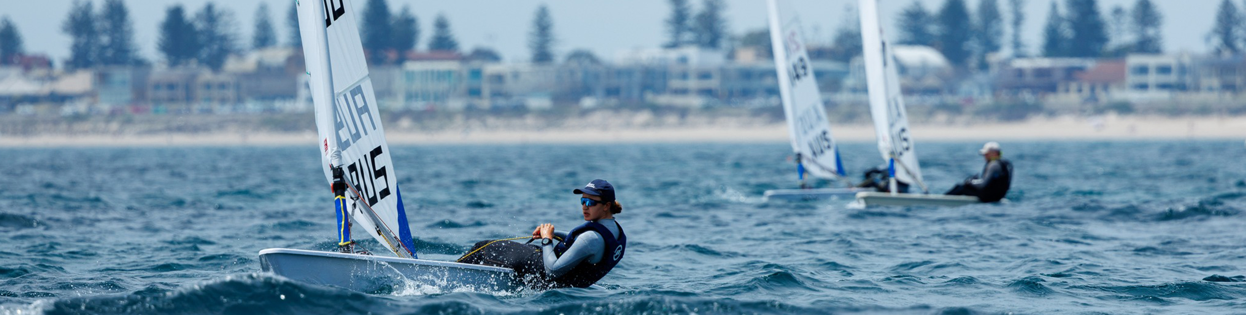 Woman on a sailing boat in the water with other boats behind her