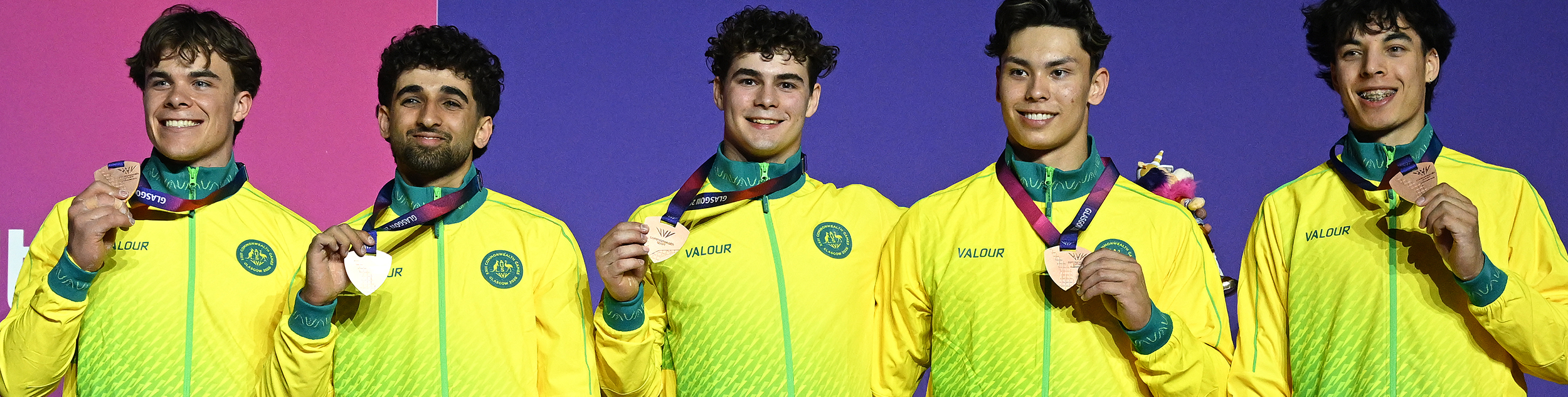 Athletes standing on podium with bronze medal