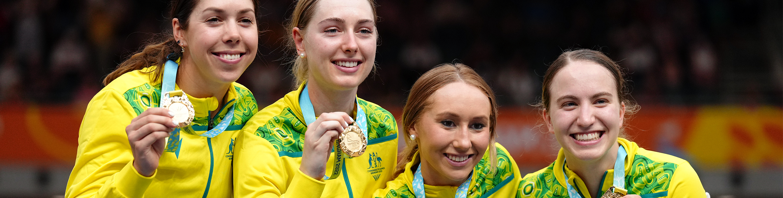 Four female athletes holding up gold medals